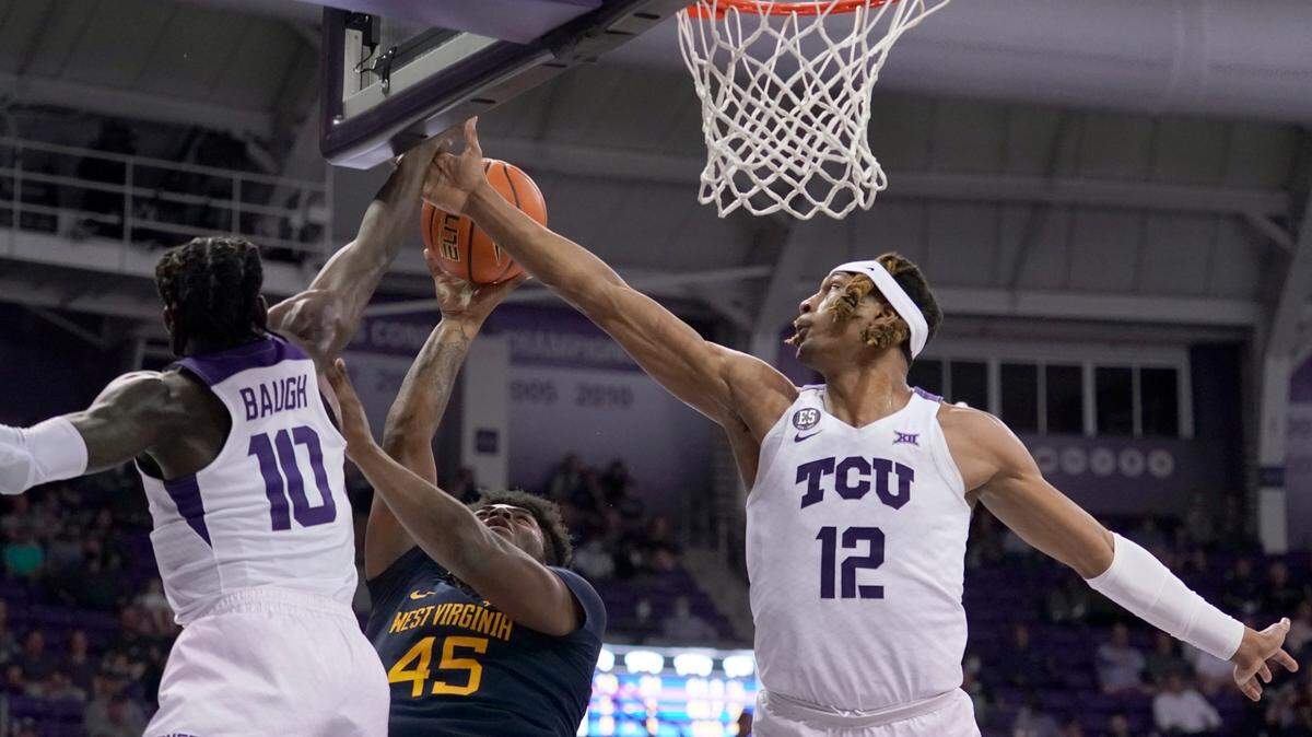 TCU guard Damion Baugh (10) and forward Xavier Cork (12) defend against a shot by West Virginia guard Seth Wilson (45) in the first half of Monday’s game in Fort Worth.