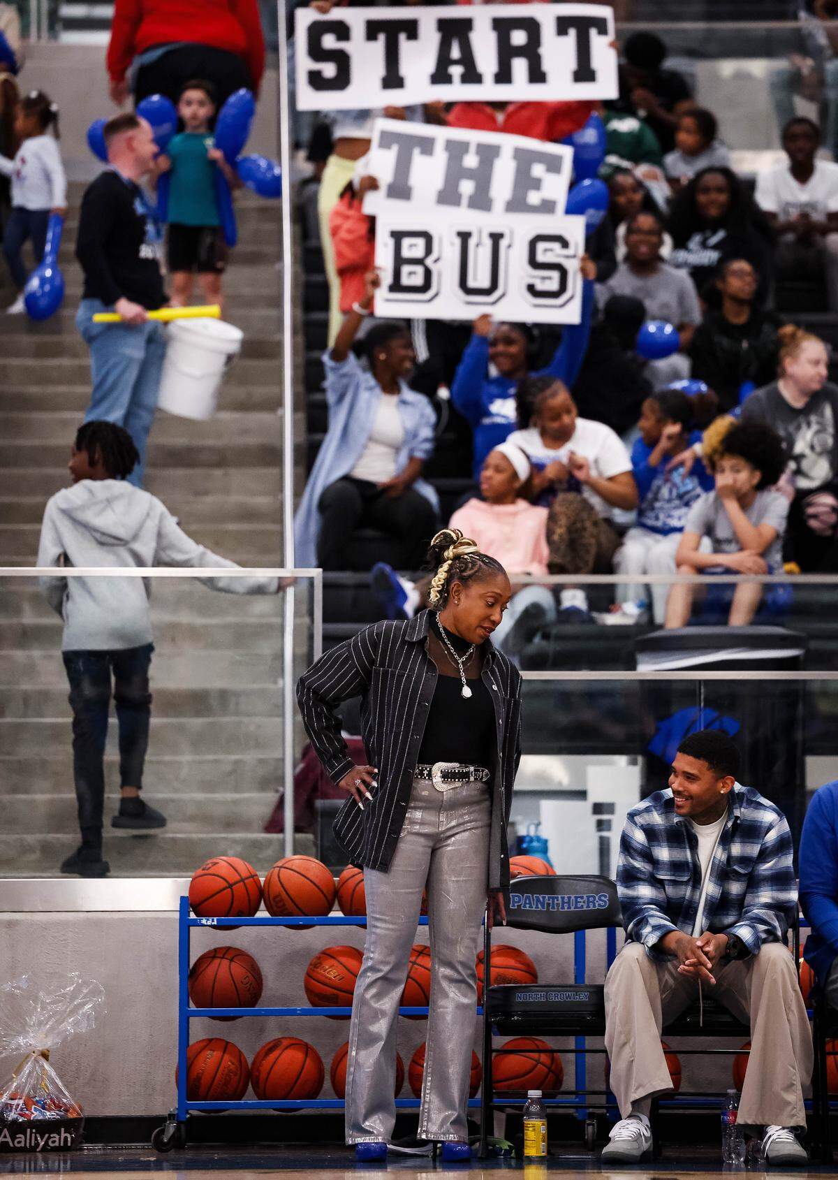 North Crowley head coach Lori Shead talks to her assistant coach while fans behind her hold a sign during a District 3-6A matchup against Weatherford on Friday at North Crowley.