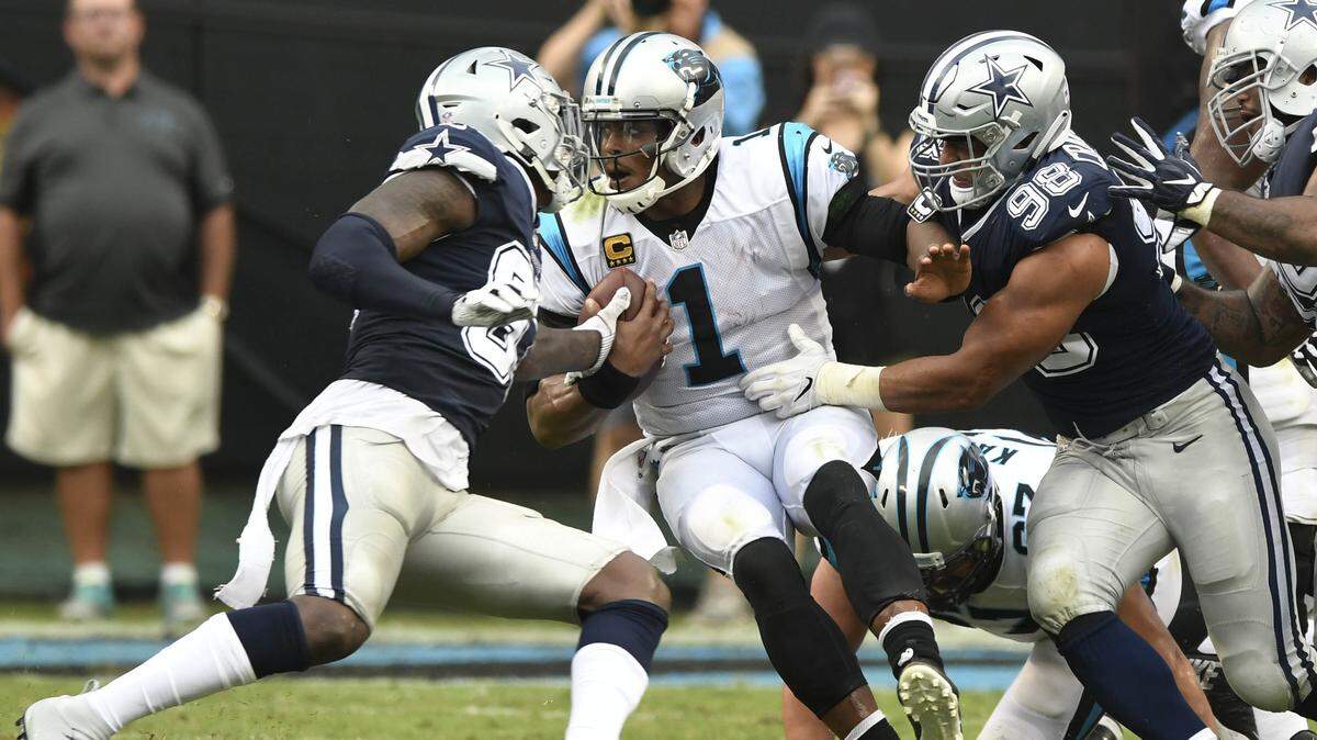 Carolina Panthers quarterback Cam Newton rolls out of pressure from Dallas Cowboys defensive end Tyrone Crawford, right, during the first half at Bank of America Stadium in Charlotte, N.C.