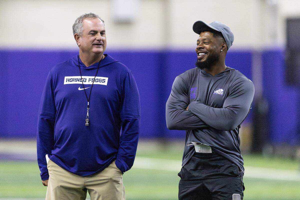TCU Head Coach Sonny Dykes stands beside another coach, both are smiling.