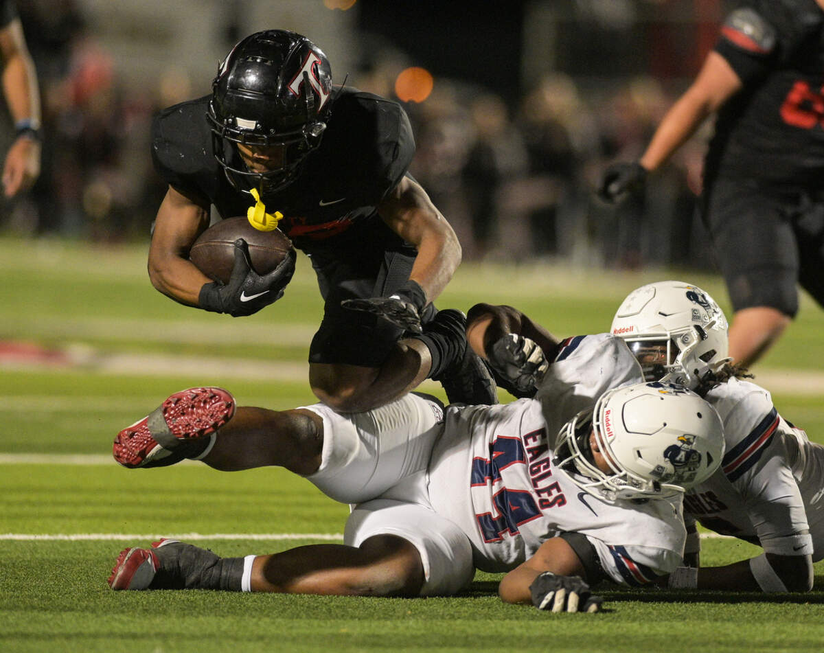 Trinity running back Joshua Bell (20) dives over Allen middle linebacker Chandler Bryant (44) during a UIL football playoff game against Allen High School at Dragon Stadium in Southlake, Texas on Friday, Nov. 29, 2024.