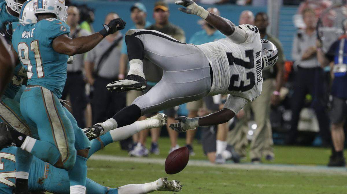 Former Oakland Raiders offensive tackle Marshall Newhouse, right, trips over Miami Dolphins middle linebacker Kiko Alonso and fumbles the ball during a game on Nov. 5, 2017, in Miami Gardens, Fla.