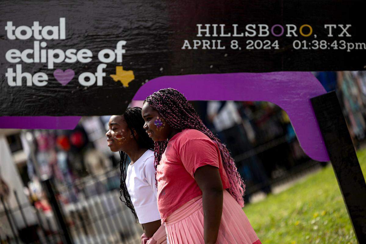 Sisters Alexus and Aniyah Williams from Seattle take a photo under the giant eclipse glasses photo spot outside the Hillsboro courthouse on Monday, April 8, 2024.