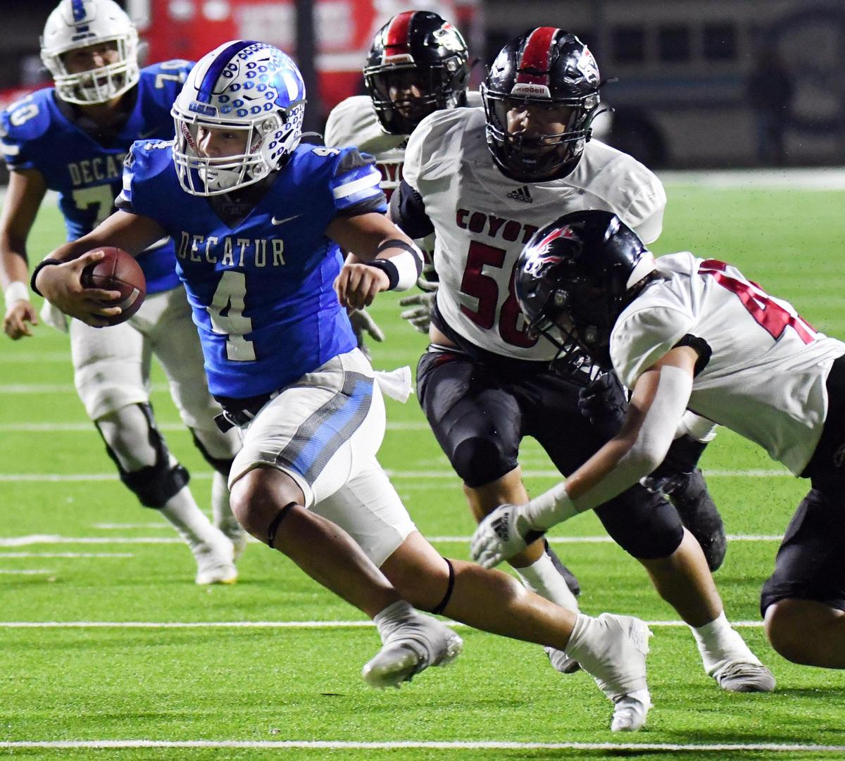 Decatur quarterback Preston Escobar, left, races away from Wichita Falls’ Victor Marquez and Gabe Milyiori foar a first down in the third quarter of Friday’s December 2, 2022 4A Division 1 state quarterfinal football game at the Collins Athletic Complex in Denton, Texas. Decatur went on to win 35-21. Special/Bob Haynes