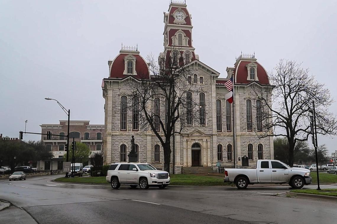 Cars drive around the Historic Parker County Courthouse Tuesday, March 17, 2020, in Weatherford.