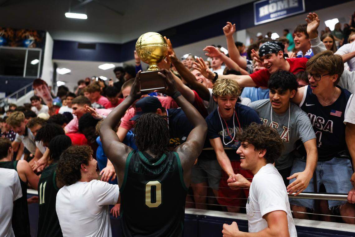 Birdville forward Gabriel Zachariah (0) holds the trophy in the air surrounded by his teammates and fellow students after clinching a spot in the state semifinals after a 50-49 UIL Class 5A Division I regional final win against Denton at Flower Mound High School in Flower Mound, Texas, Friday, March 6, 2026.