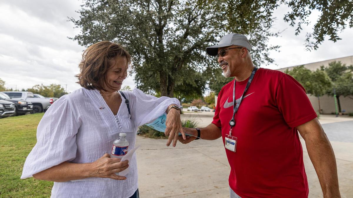 Tarrant County resident Lisa Meester accepts a flyer from Delandro Payne, a union worker at General Motors, in front of the voting site at the Tarrant County Sub-courthouse in Mansfield on Wednesday, Oct. 30, 2024.