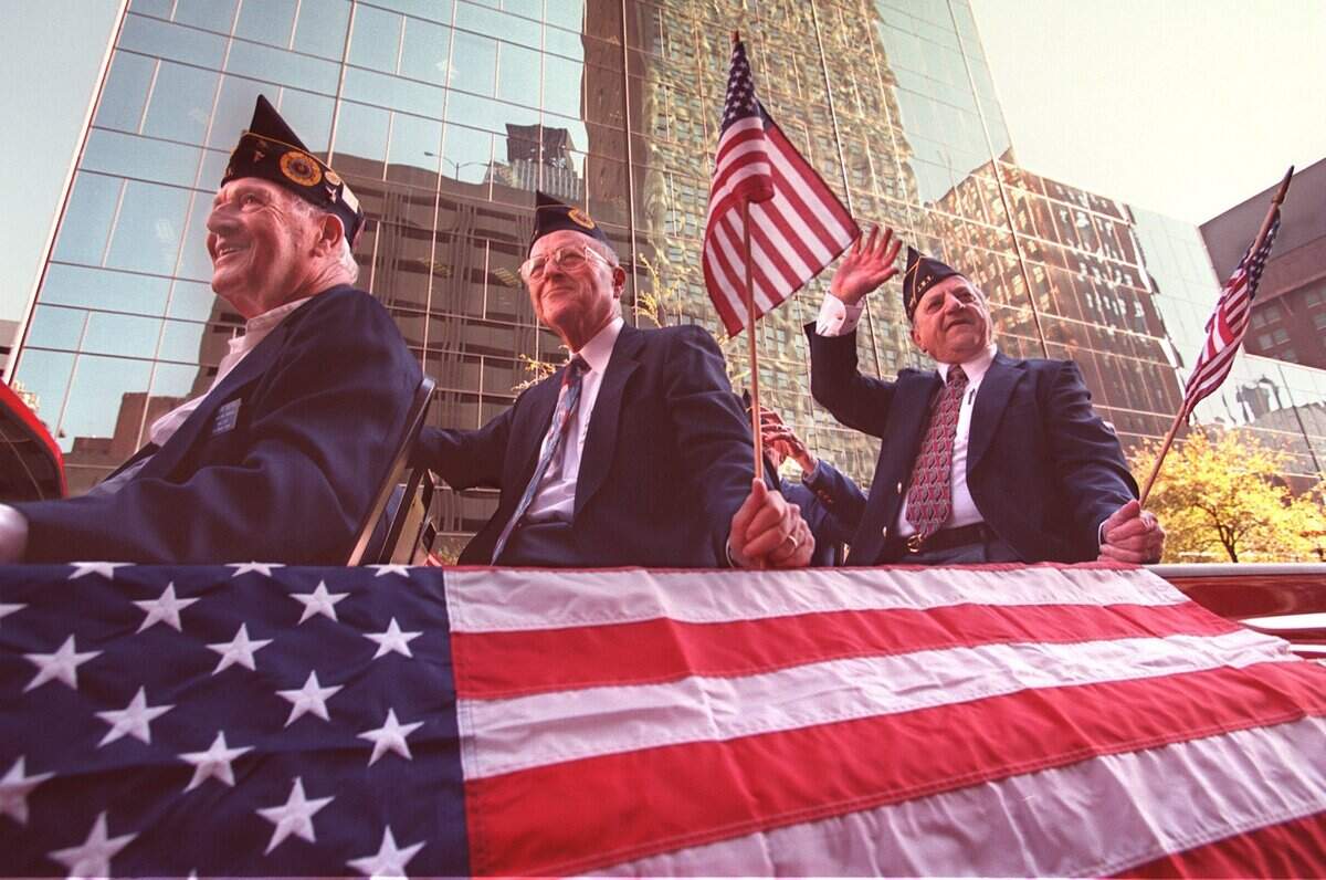 Nov. 11, 1999: Fort Worth residents Sam Berg, left, Irv Bodzy and Sam Blinderman of the Jewish War Veterans Post 755 ride in the rear of a pickup covered in a large flag as they make their way up Main Street in downtown Fort Worth during the Veterans Day Parade.