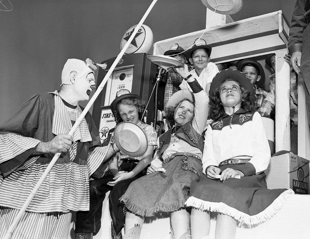 Mr. Edwards is holding a pole with what appears to be plates in the shape of UFOs. The children are looking at the objects while seated on a parade float.