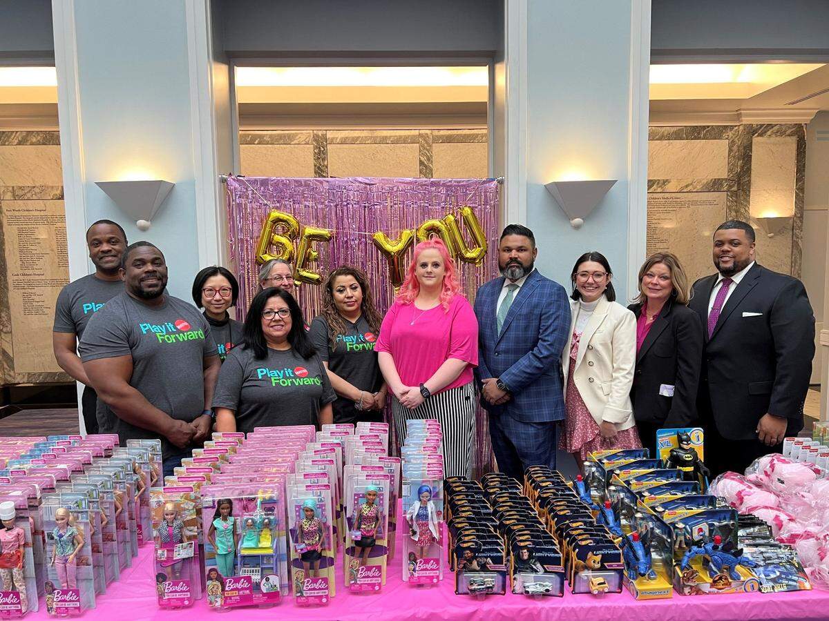 A group of people standing in front of table filled with toy donations. 
