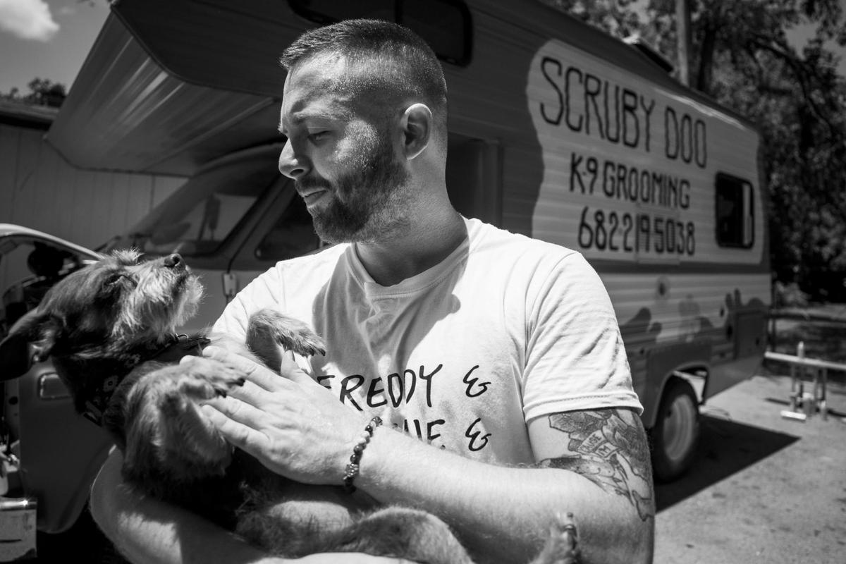 Chase Brooks plays with his dog while building his mobile dog grooming vehicle. Brooks worked for groomers who had to close permanently amid the coronavirus outbreak. He is starting his own business.