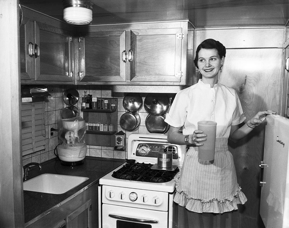 Feb. 13, 1954: Preparing meals is no problem for Mrs. W. P. Hamilton, as she gets fruit juice from the refrigerator and starts to prepare breakfast for her husband at their mobile home.