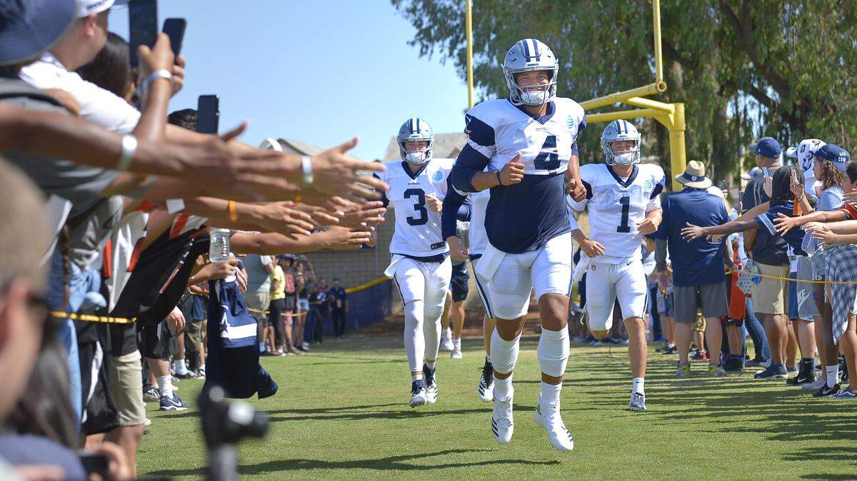 Dallas Cowboys quarterback Dak Prescott (4), quarterback Mike White (3) and quarterback Dalton Sturm (1) run through a line of VIP fans during the afternoon scrimmage at training camp in Oxnard, CA, Sunday, Aug. 5, 2018.  
