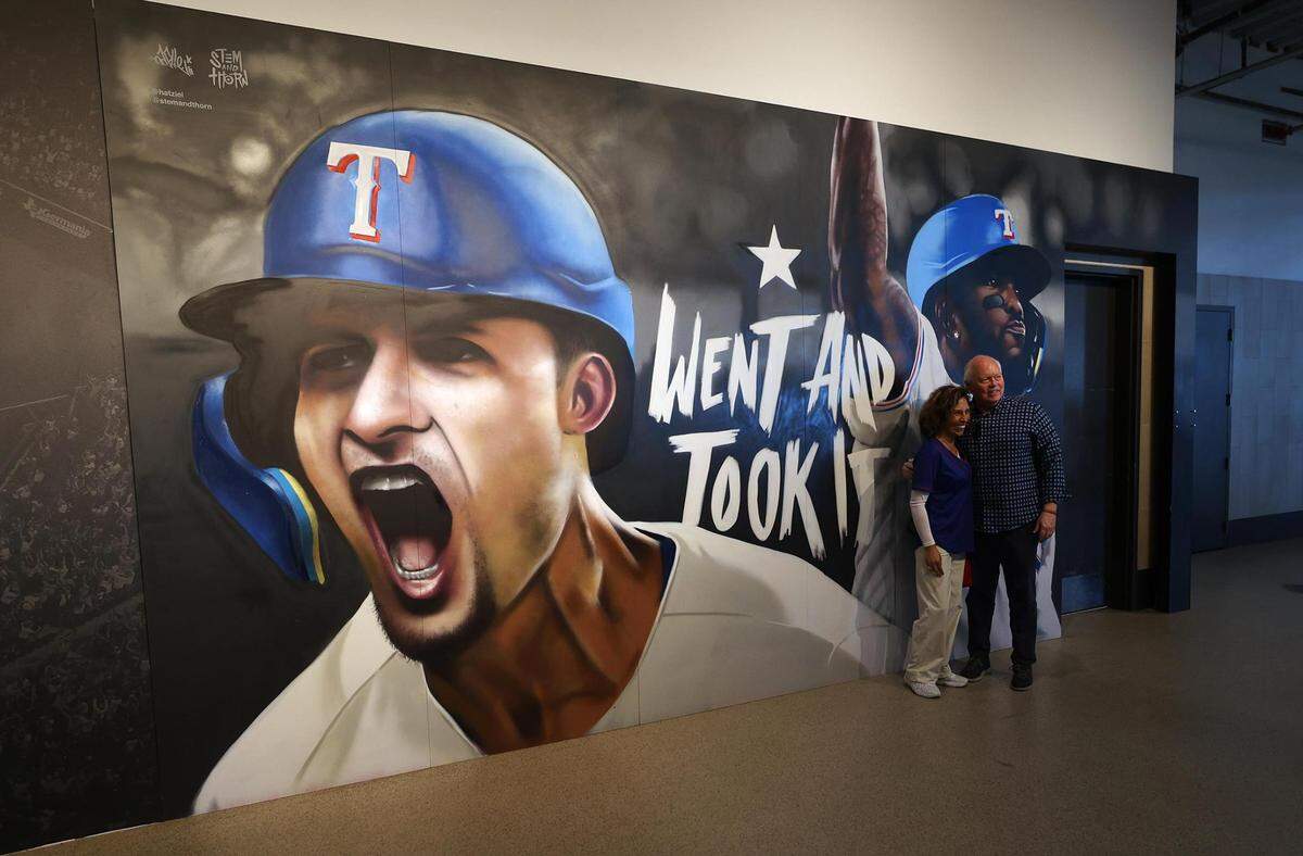 Texas Rangers fans take a photo next to a mural at Globe Life Field on Thursday, March 28, 2024, at Globe Life Field in Arlington.