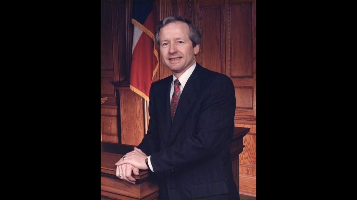 A lawyer posing for a portrait leaning on a banister