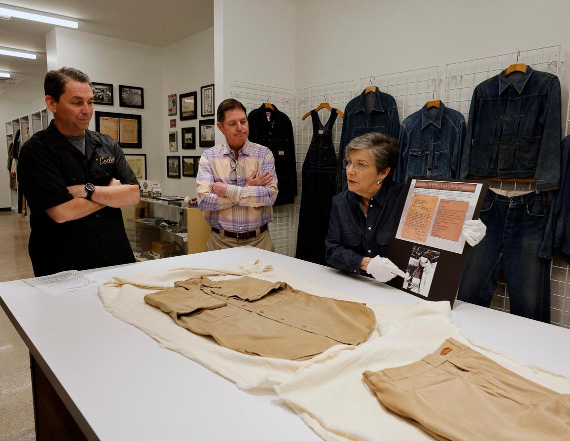 Archivist Ann Richardson talks about a work suit of shirt and pants as Dickies Global Brand President Todd Dalhausser and brand ambassador Philip Williamson look on at Dickies offices in downtown Fort Worth Texas, Thursday Mar. 28, 2024. The apparel was returned to the company by the original purchaser. It was worn 14 years. He thought it would be a good advertisement to the company and hoped they would send him a replacement. The 102 year old work apparel company recently relocated to downtown Fort Worth. (Special to the Star-Telegram Bob Booth)