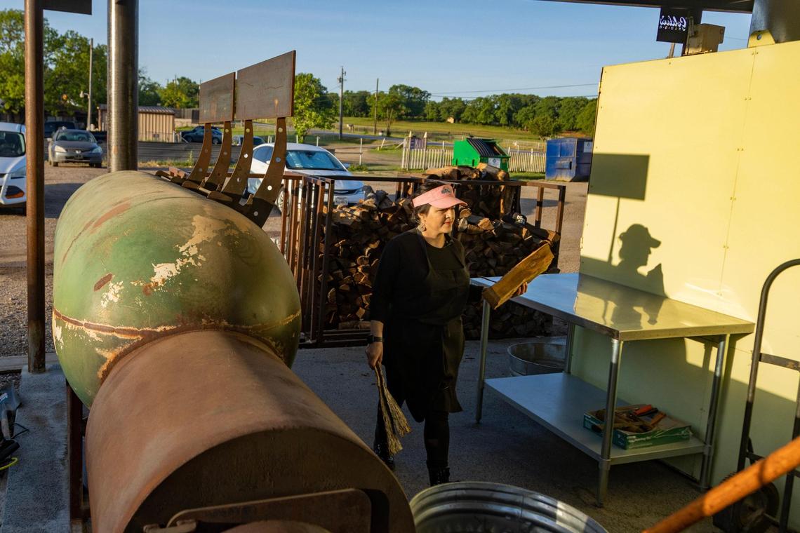 Pitmaster Cecilia Guerrero grabs logs to add to the smoker at Goldee’s Barbecue in Fort Worth on Saturday, April 22, 2023.