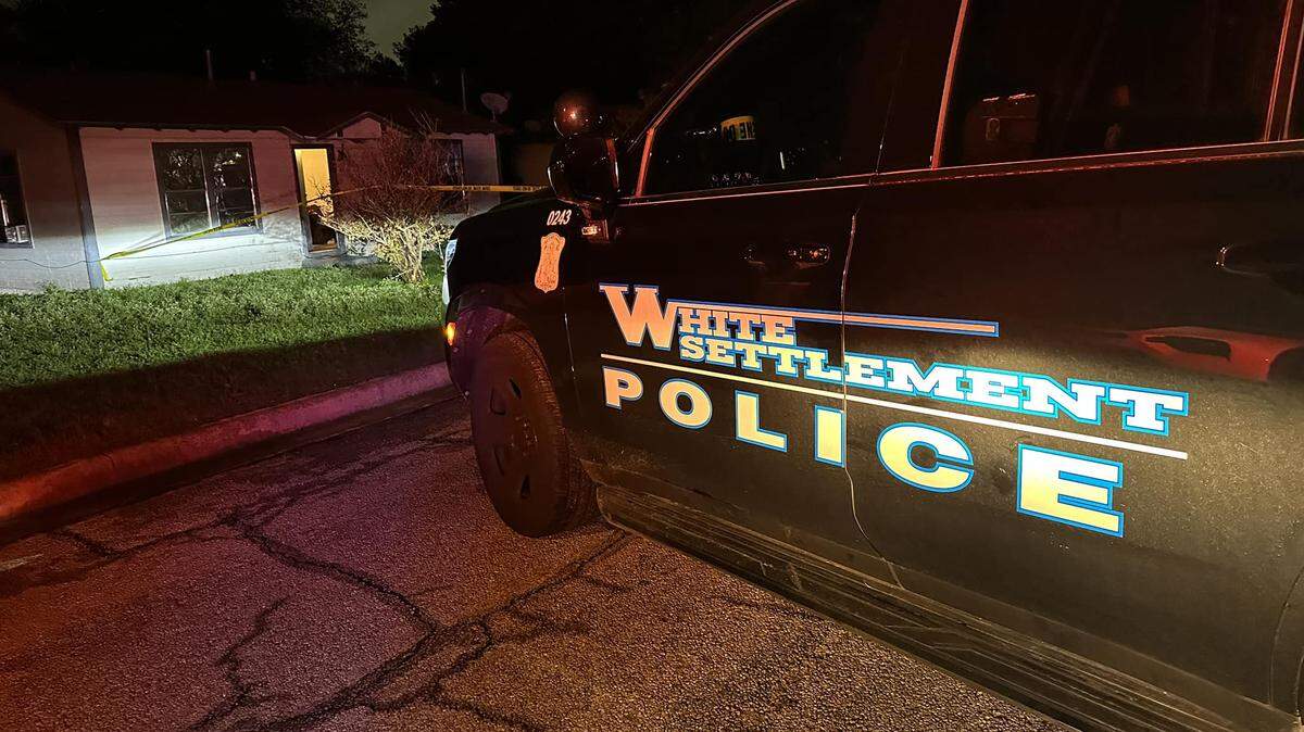 A White Settlement police car sits outside a house.