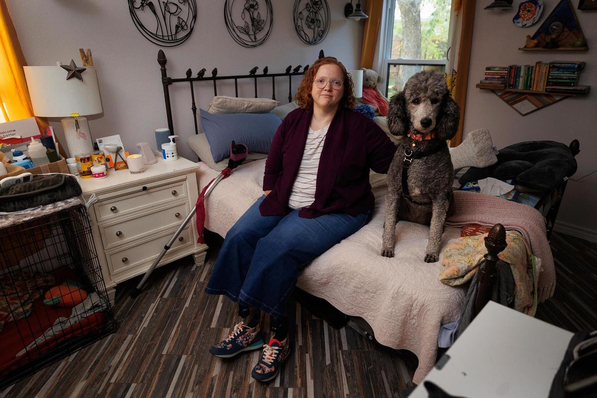 Melissa Dossey sits with her service dog Coraline, while wearing her new prosthetic legs on Wednesday, April 9, 2025, in North Richland Hills. Dossey said losing her physical therapy team "would have been just catastrophic."