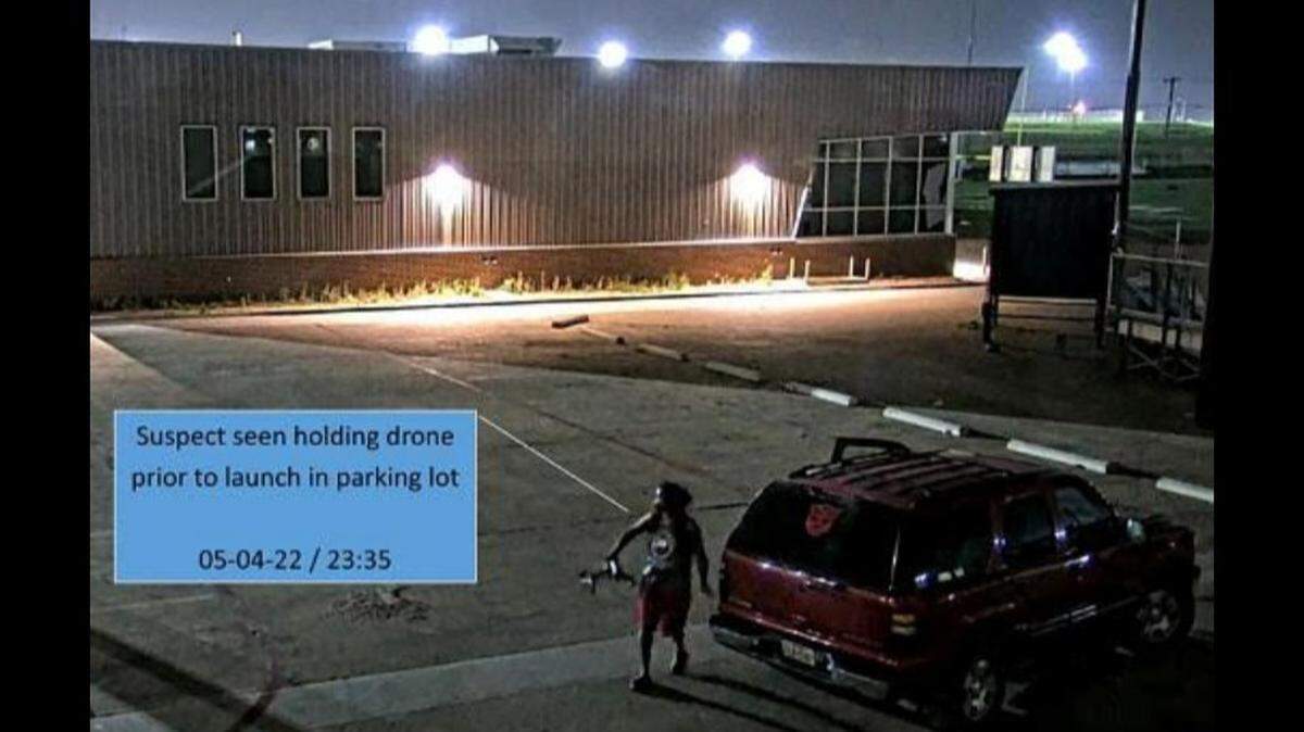 A surveillance image captured a young man drive up in a red Chevy Tahoe with a Transformers decal on the rear window, remove a drone and a package from the vehicle, and launch the drone toward a prison facility in Fort Worth on May 4, 2022, according to federal authorities.