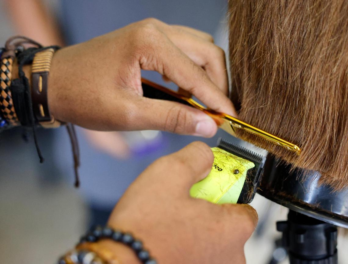 Camden Jones, 14, trims the back of his mannequin head’s hair at Next Level Barber and Cosmo camp in Fort Worth.