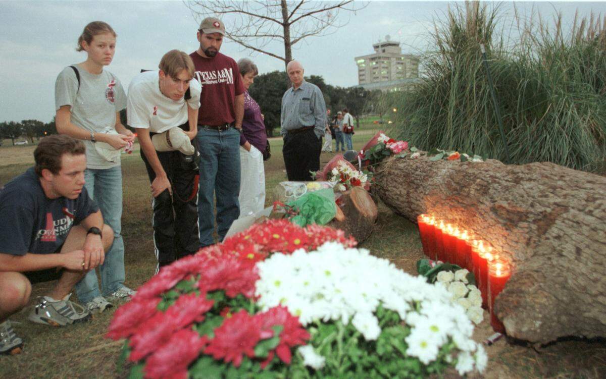 People gather to read a note on a makeshift memorial near the scene of the bonfire accident at Texas A&M on Nov. 18, 1999.