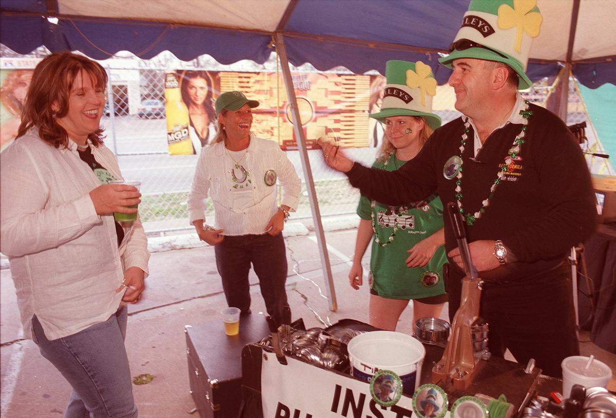 March 17, 2003: Loralee Melsen and Glenda Grubbs put on a button made by Michelle McIntosh and Des O’Neill at the J. Gilligan’s St. Patrick’s Day festivities in Arlington.