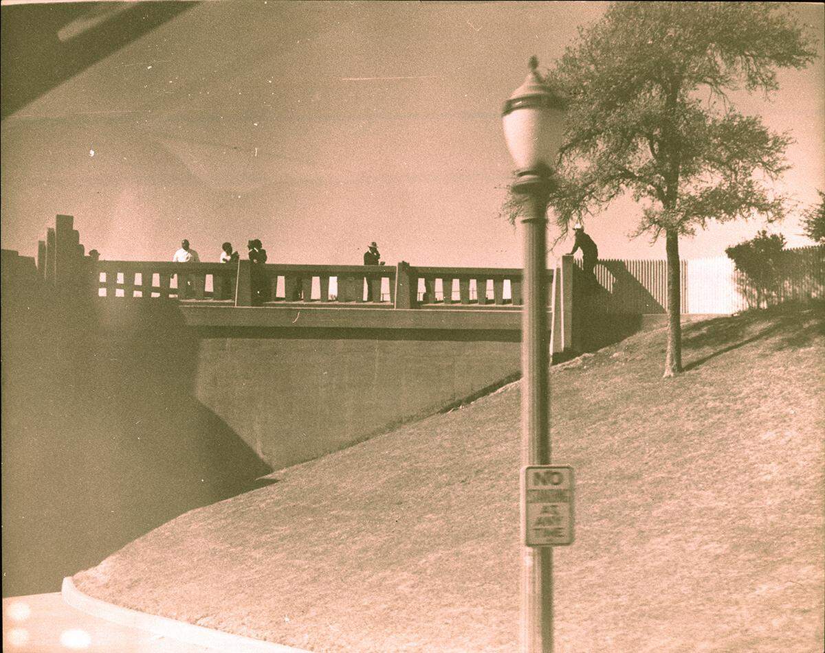 Nov. 22, 1963: Photo taken from moving press bus, people standing on the bridge overlooking grassy knoll after President John F. Kennedy’s assassination.