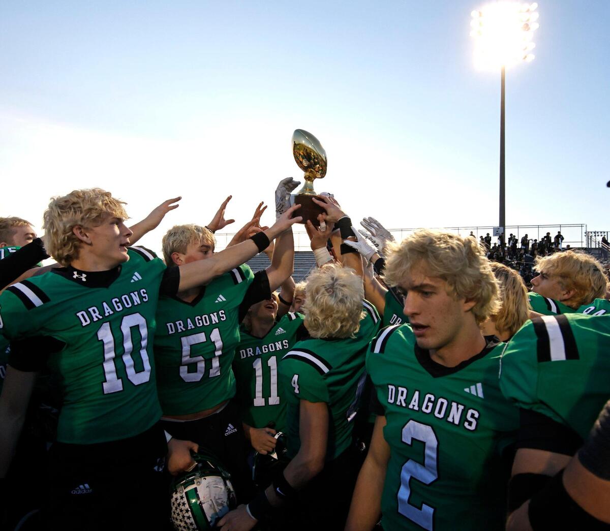 Dragon players reach for the trophy after winning the UIL District 6A D2 Regional Semi-Finals football game at Joy and Ralph Ellis Stadium in Irving, Texas, Nov. 29, 2024.