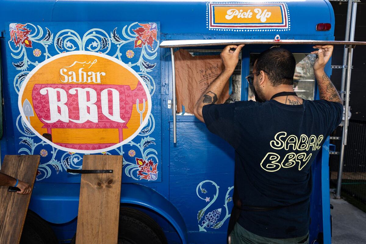 Pit hand Usama Khalid begins to open the windows at the Sabar BBQ trailer parked at the corner of E Vickery Street and S Main Street near downtown Fort Worth on Saturday, Aug. 31, 2024.