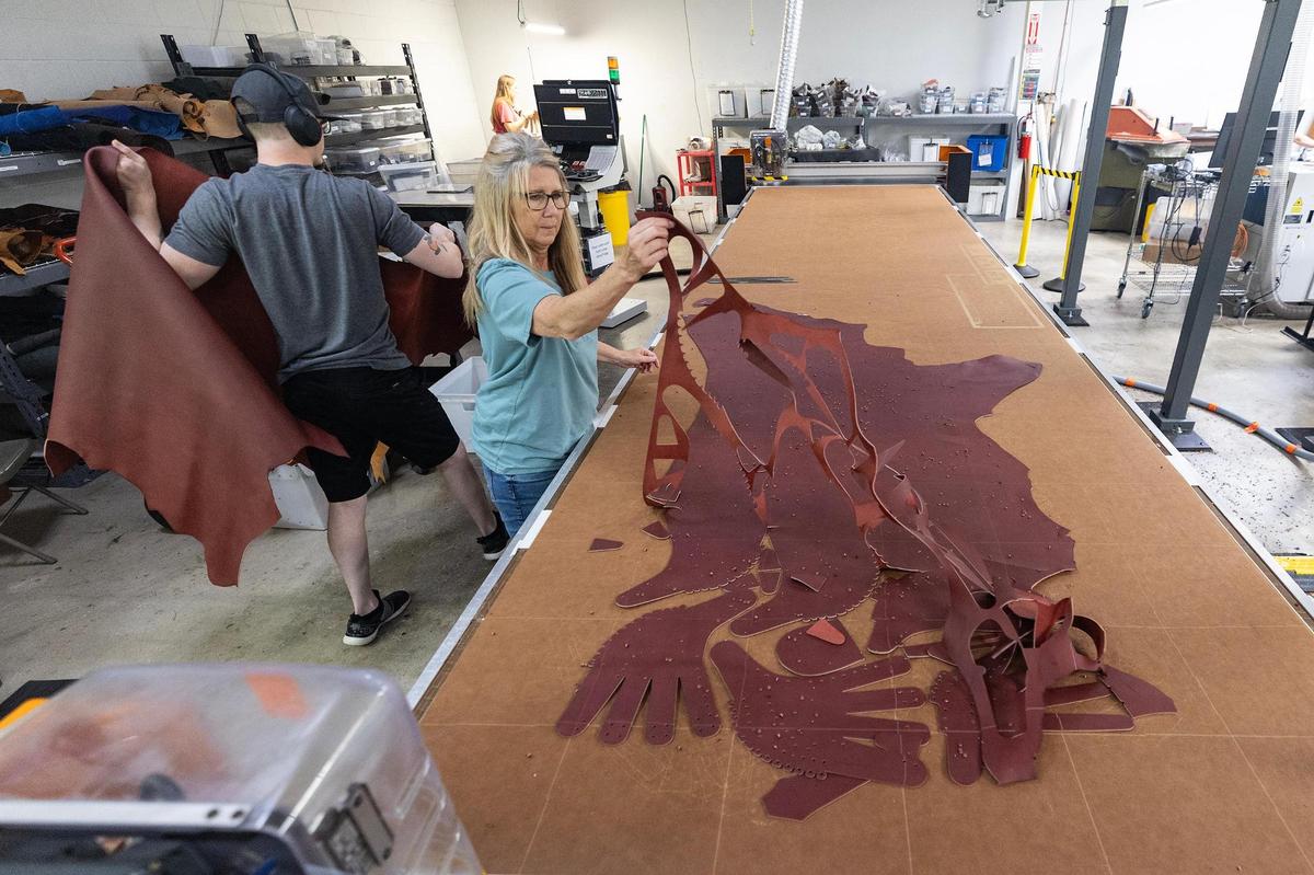 Tracey Johnson peels back the cowhide that was cut into baseball glove pieces using a flash cutter machine.