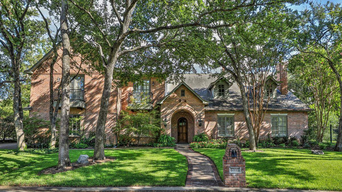 The home at 6105 Laurel Valley Court features a graceful front yard with towering trees and manicured landscaping.