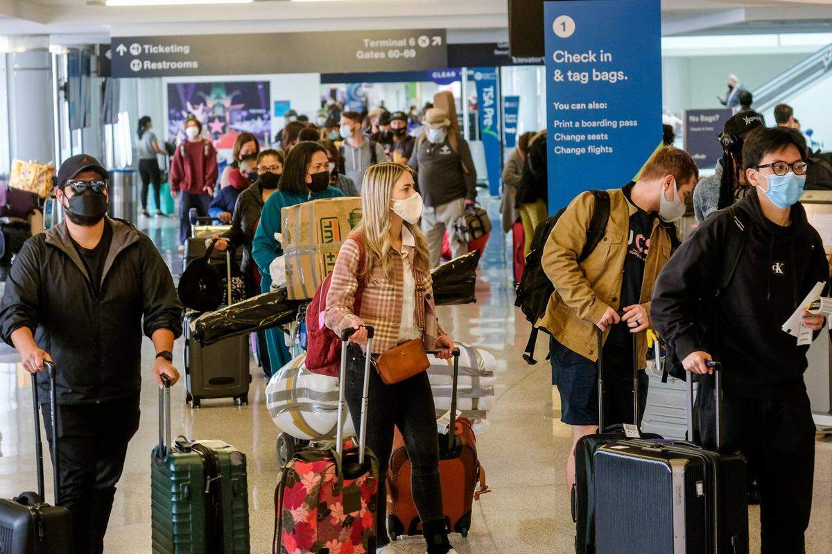 Holiday travelers wearing face masks line up to check in Dec. 22 at the Los Angeles International Airport in Los Angeles. (AP Photo/Ringo H.W. Chiu)