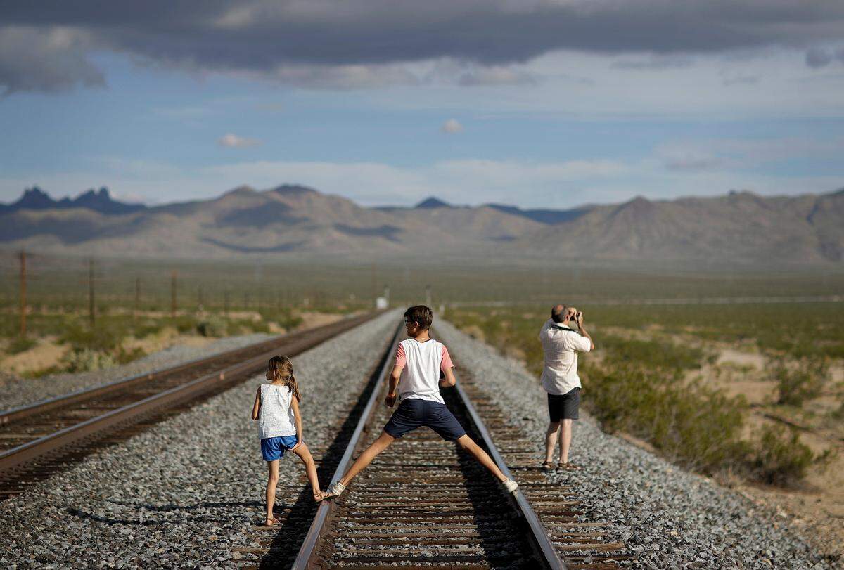 A family walks along train tracks, Thursday, Aug. 3, 2017, in Nipton, Calif. (AP Photo/John Locher)