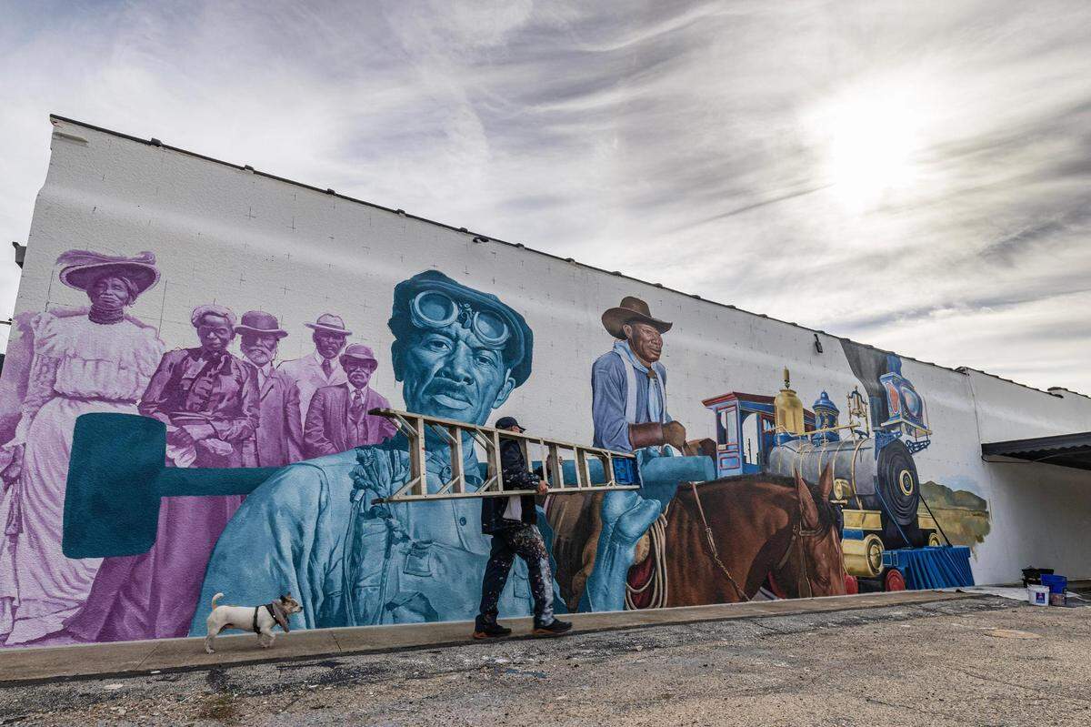 Artist Armando Castelan finishes a mural intended to portray members of the Black community who worked hard in the face of adversity.