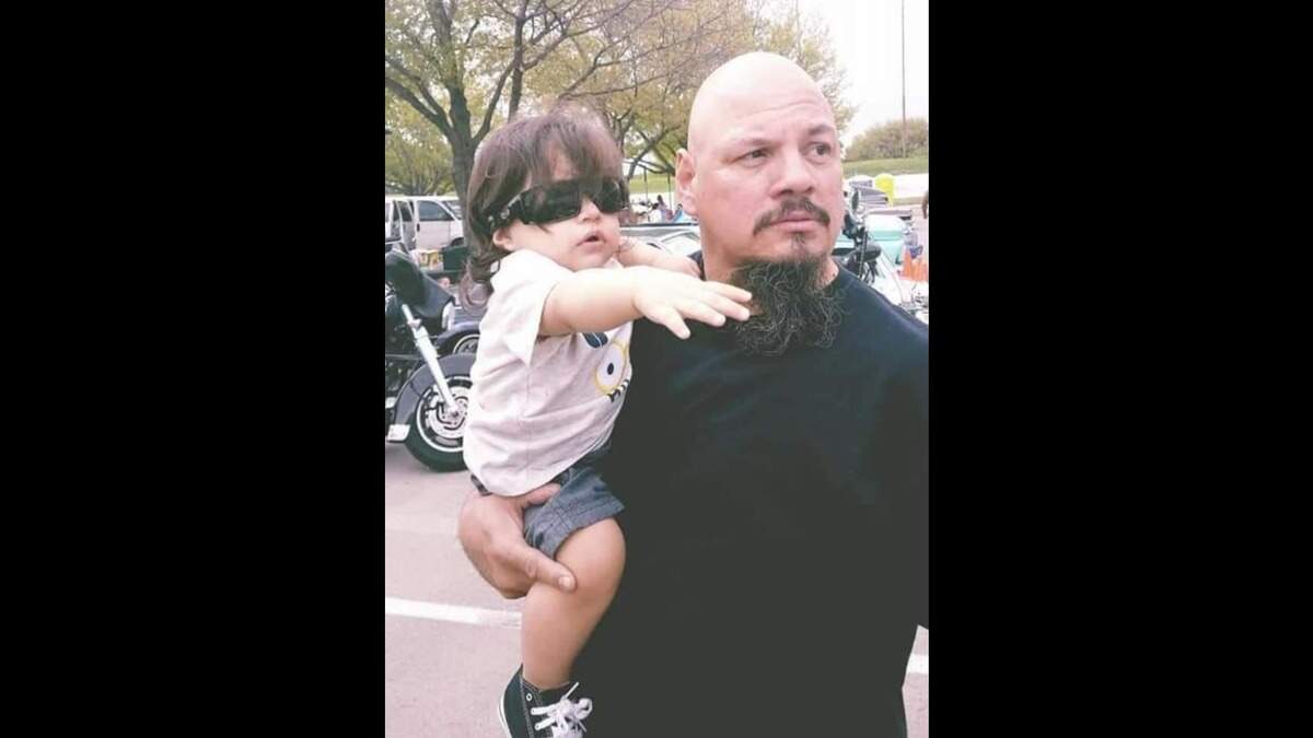 Henry Lopez (right) holds his grandson, Oliver Rosales. His daughter, Maria Rosales, had the baby three years ago, and chose a middle name, Lee, to honor her brother, Johnny Lee Lopez.