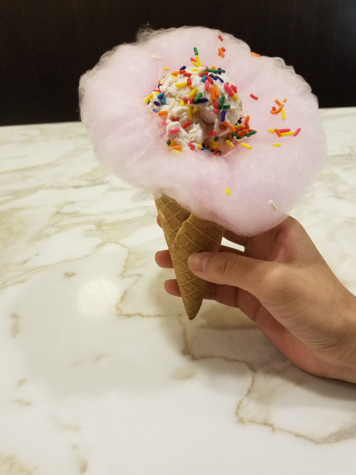 A Cloud Cone — a waffle cone wrapped in house-made cotton candy — at Hypnotic Emporium. The Hypnotic Donuts spinoff, which sells classic candies as well as ice cream, recently opened a Mansfield location.