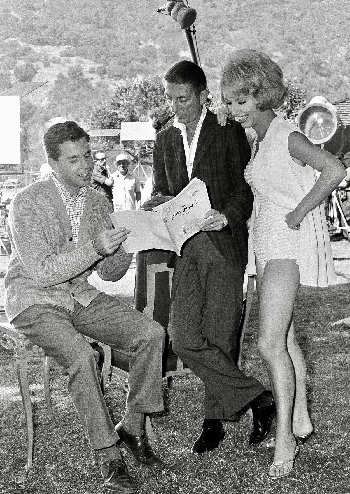 Producer Aaron Spelling, center, goes over script of NBC-TV’s “Crazy Sunday, “ with director Jeffrey Hayden, as Ruta Lee looks on, ready to take her part in the filming of the episode on Oct. 4, 1962.
