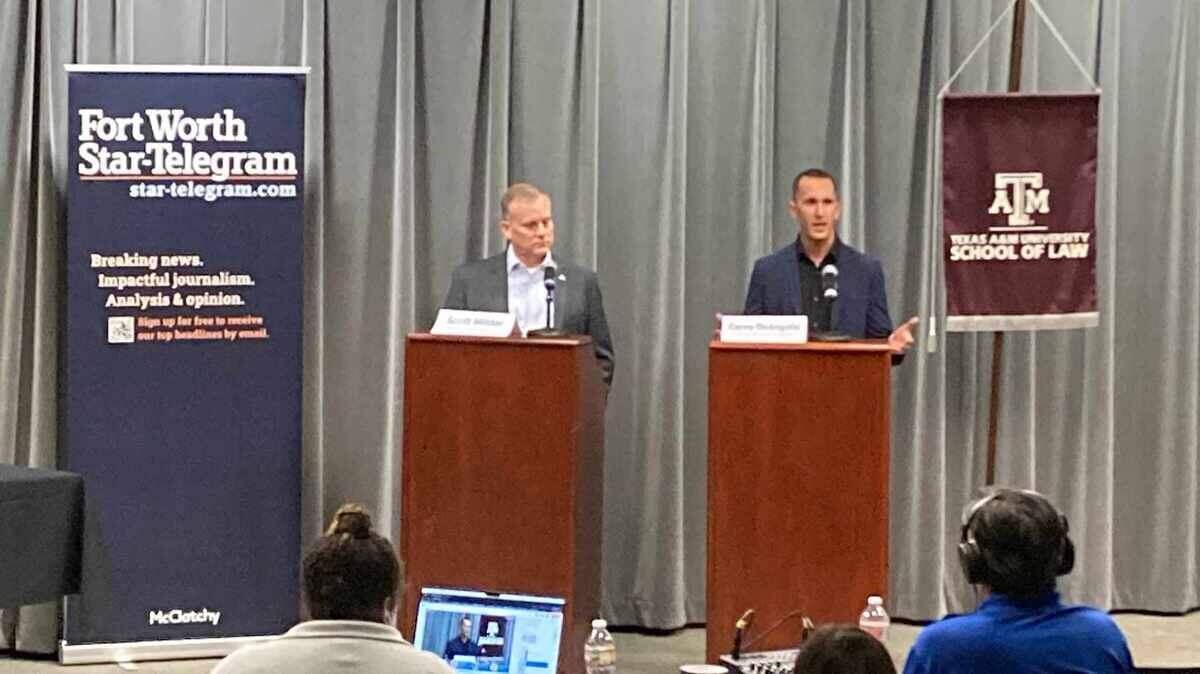 Two men stand behind brown lecterns on a dais. Banners for the Fort Worth Star-Telegram and the Texas A&M University Scool of Law hang on either side of them.