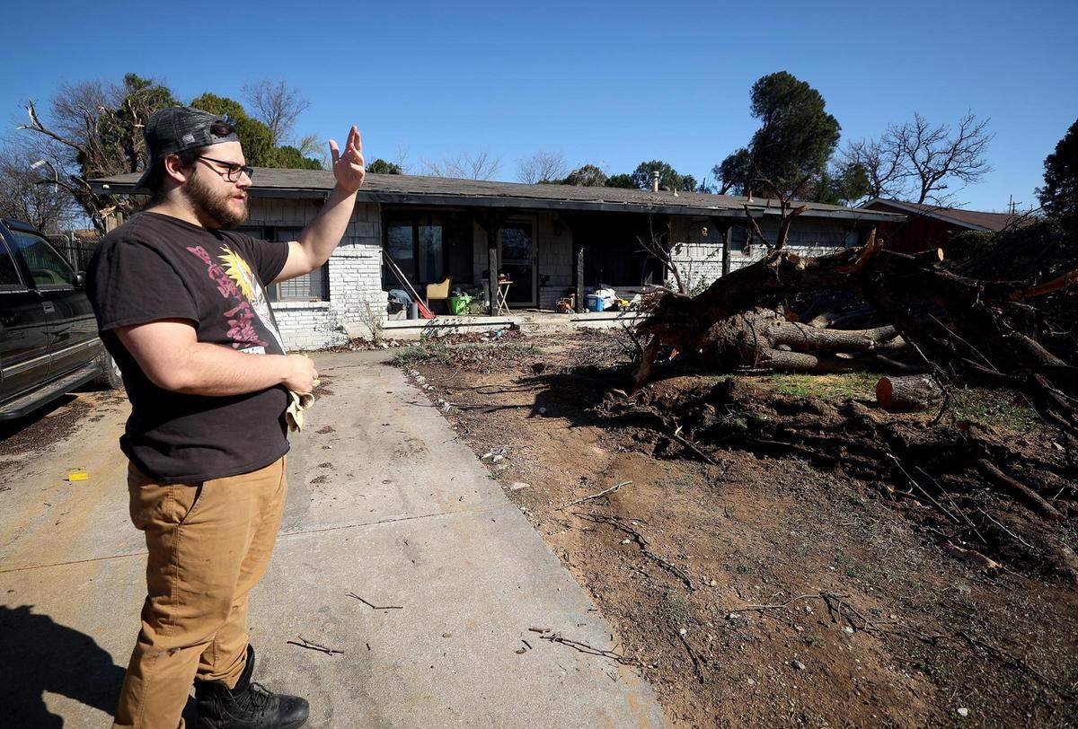 Sean Bannister works to clean up his yard on Wednesday, March 23, 2022, after a tree was blown down during Monday night’s storm. A handful of homes in the neighborhood had damage following a tornado Monday evening.