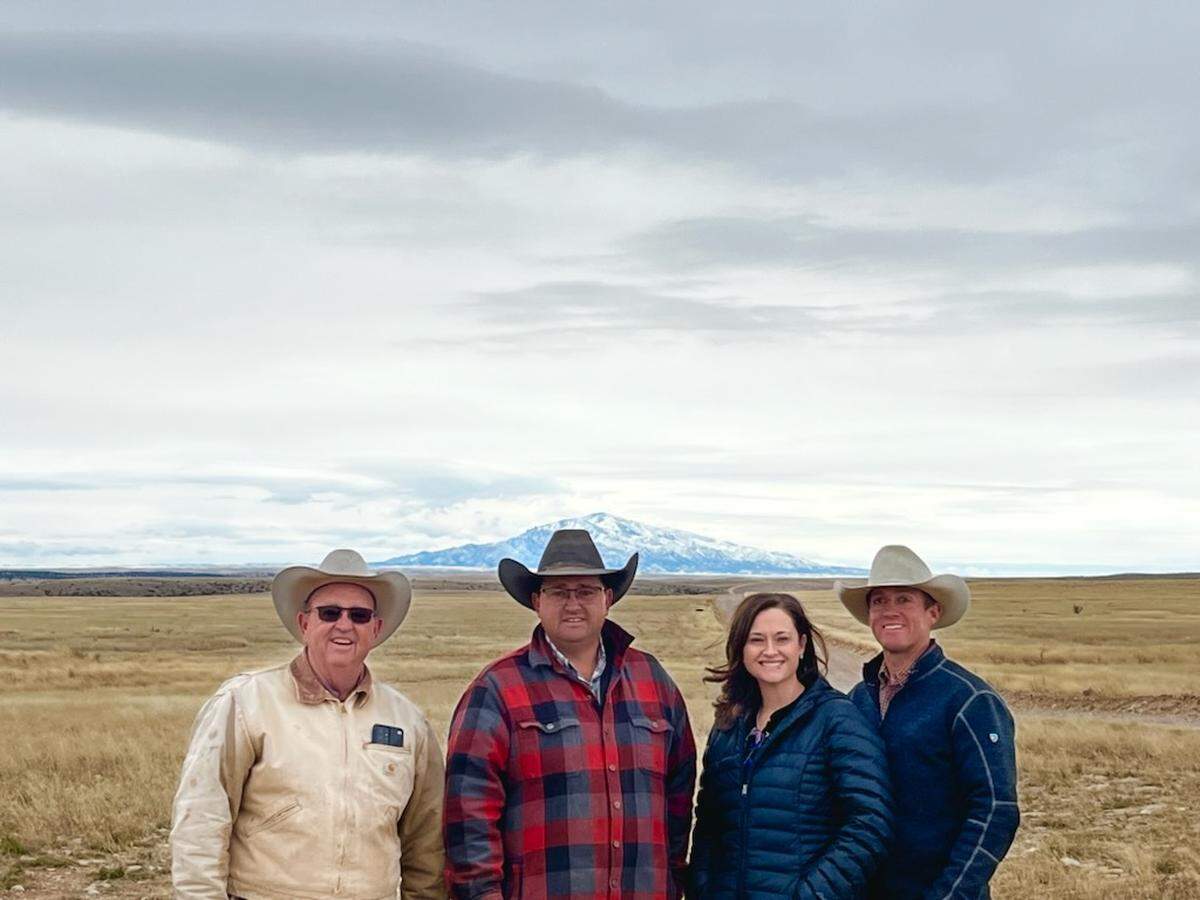 A photograph of TCU Ranch Management alumnus Mike Corn and his family at their ranch near Roswell, New Mexico, with a snow-capped peak in the distance. 