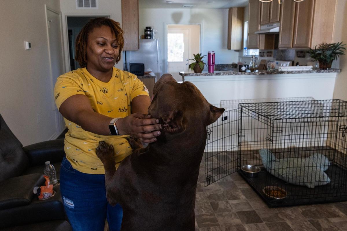 Smith pets her dog Mocha in the living room of her new home in Fort Worth. Mocha has already befriended other dogs on the block, Smith says.