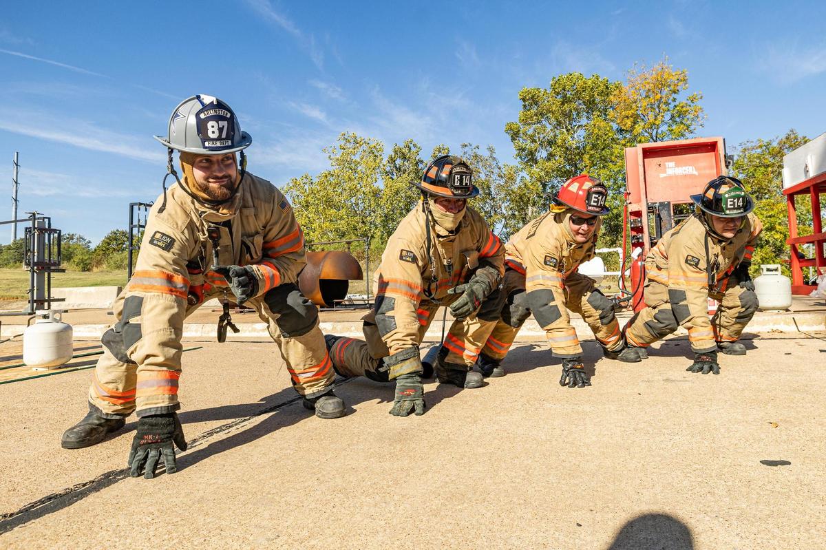 Dallas Cowboys tight end Jake Ferguson, left, lines up in a three-point stance with Arlington firefighter Lonnie Ballenger, second from left, Lieutenant Monty Stayner, second from right, and firefighter Jeremy Contreras for a picture during a Turkey Fryer Fire Safety demonstration at the Arlington Fire Department Training Facility Station 14 in Arlington on Tuesday, Nov. 14, 2024.