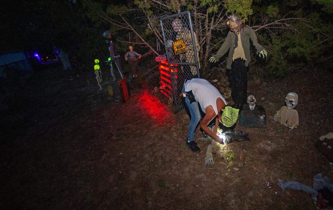 Chris Caughlan makes a final walk-through her “Twisted Crazy Haunt” dsiplays, checking batteries and making sure the animatronics are working properly.