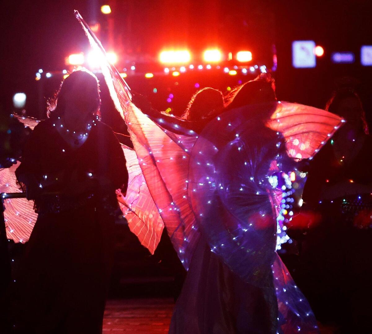 Dancers are silhouetted against Christmas lights during the 2024 Parade of Lights.