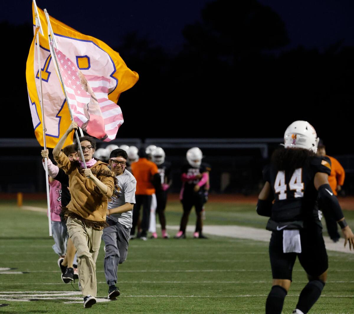 The Volunteers flag crew run the field after a touchdown during a District 8-6A football game at C.H. Wilemon Field in Arlington, Texas, Friday, Oct. 18, 2024.
