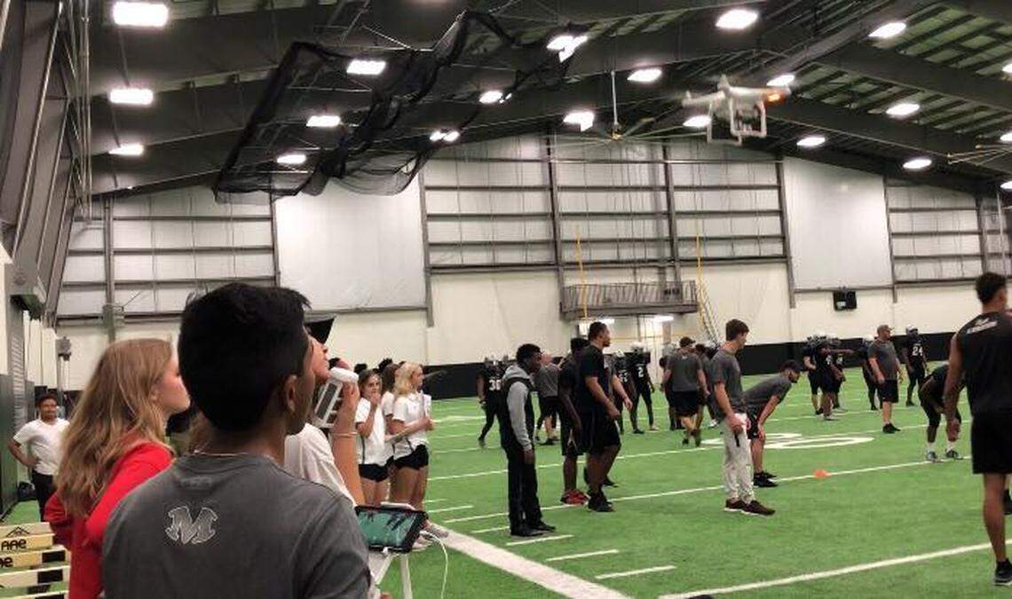 Arlington Martin junior Rajesh Murti, left, runs the team drone during a football practice, Wednesday, April 25, 2018.