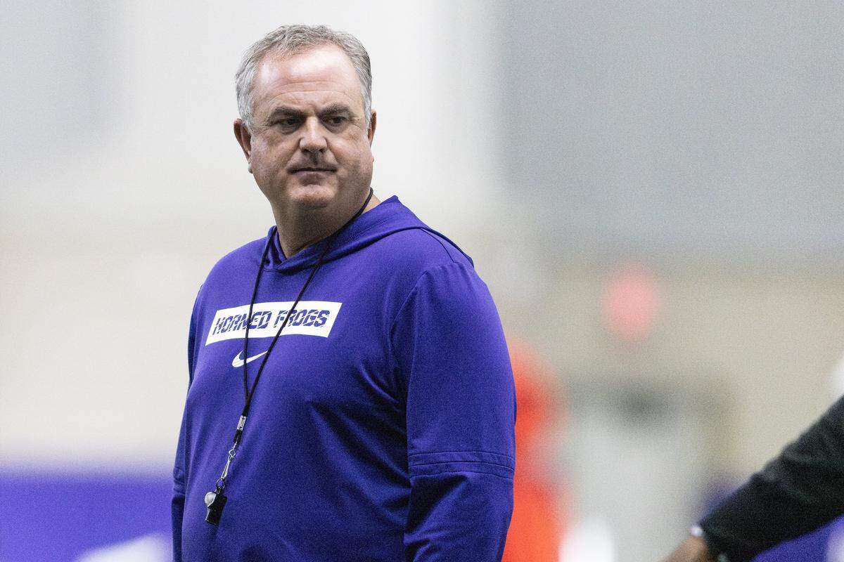 A head and shoulder view of Sonny Dykes who is wearing a purple hoodie and whistle around his neck.