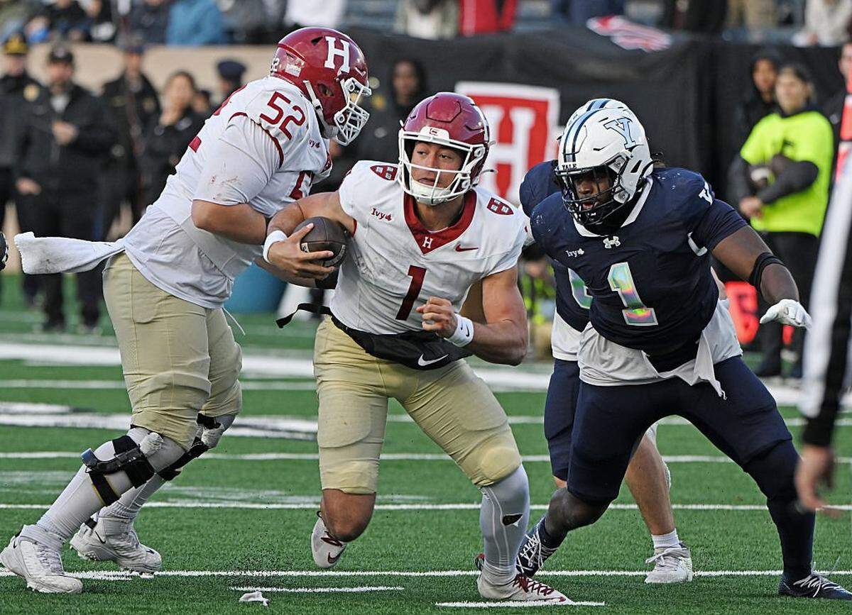 NEW HAVEN, CONNECTICUT - NOVEMBER 22: Jaden Craig #1 of the Harvard Crimson is caught between teammate Aidan Kilstrom #52 and Zairion Jackson-Bass #1 of the Yale Bulldogs in the second half of the 141st playing of "The Game" at Yale Bowl on November 22, 2025 in New Haven, Connecticut. (Photo by Sean D. Elliot/Getty Images)