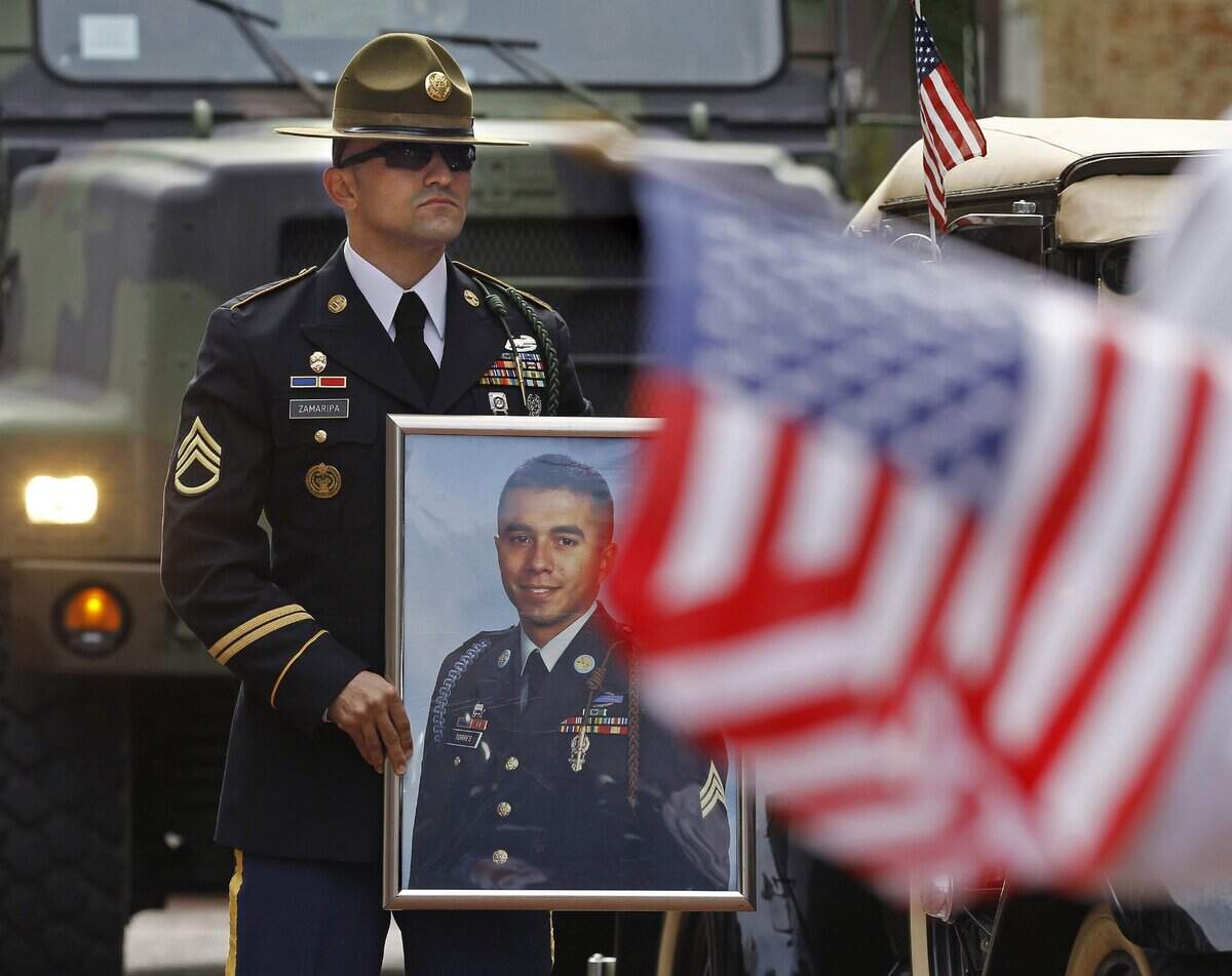 Nov. 12, 2011: As the Veterans Day parade begins, Grand Marshall Staff Sgt. Cody Zamaripa stands at attention holding a photograph of his best friend, Sgt. Daniel Torres, who was killed in Iraq. Both are from Fort Worth.